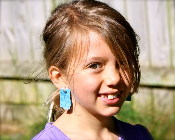 Charlotte showing her Birthday greeting to her Daddy with her earrings